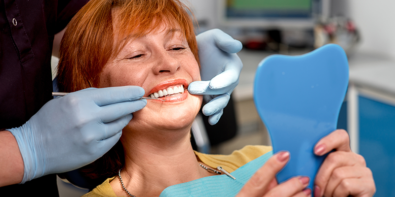 Lady seeing her smile in the handheld mirror